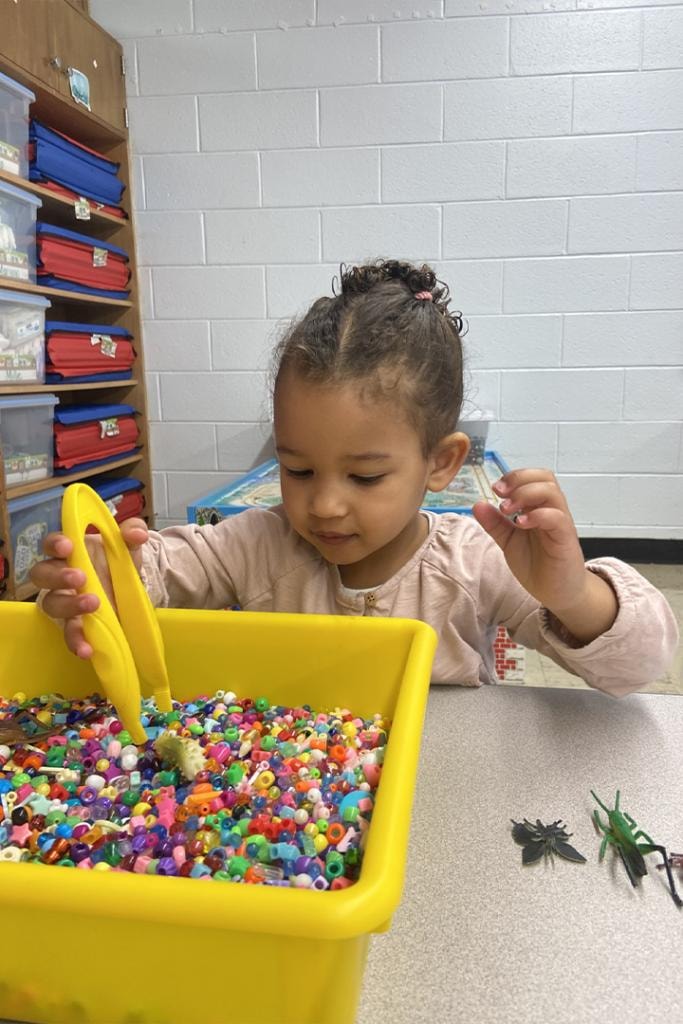 Young child playing with colorful beads