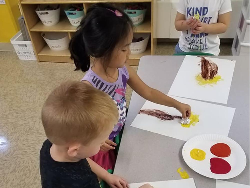 Children creating art with paint in classroom